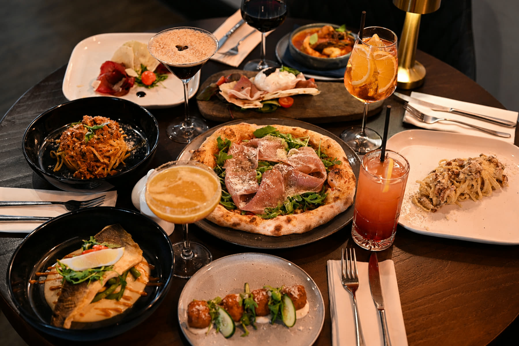 A table of pizza, pasta and cocktails